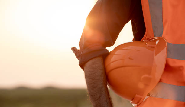 istock Close-up of engineering holding orange helmet hard hat safety during sunset background 2197408095