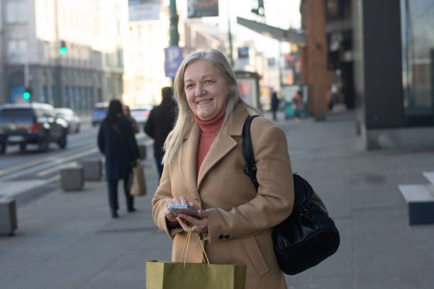 istock Senior woman texting on phone while walking outdoor 2197416225