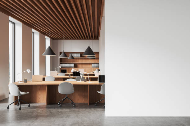 istock Empty white wall with modern office interior featuring wooden desks, chairs, shelving, and pendant lighting in neutral tones. 3D Rendering 2197416751