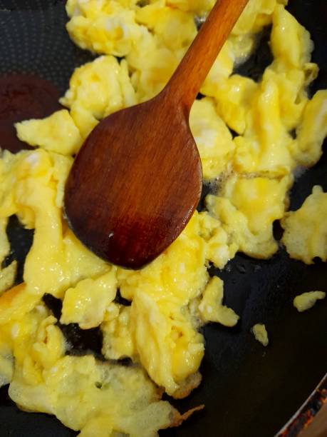 istock Scrambled eggs in frying pan with wooden spoon. 2197420064