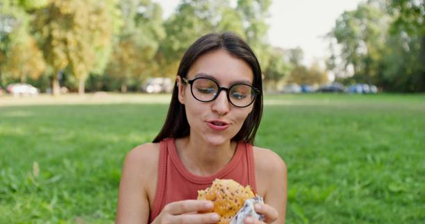 istock A woman eats a burger in the park 2197422788