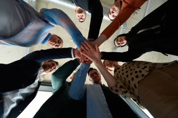 istock A group of business professionals, captured from a low angle, holding hands to symbolize unity and teamwork. 2197423450