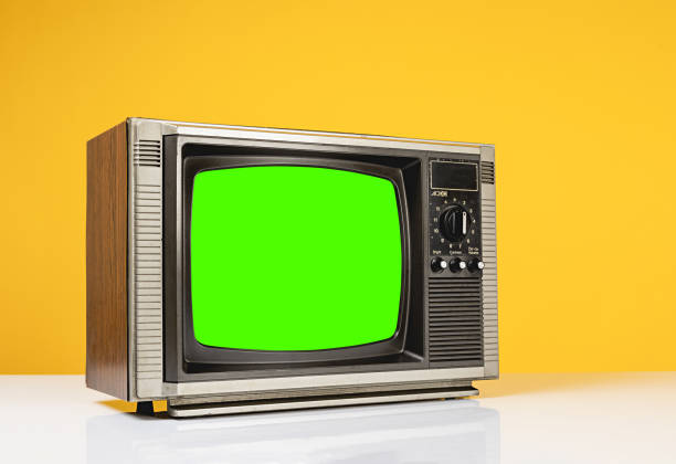 istock Old retro TV with chroma key green screen on white table with on yellow background, side view. 2197423854