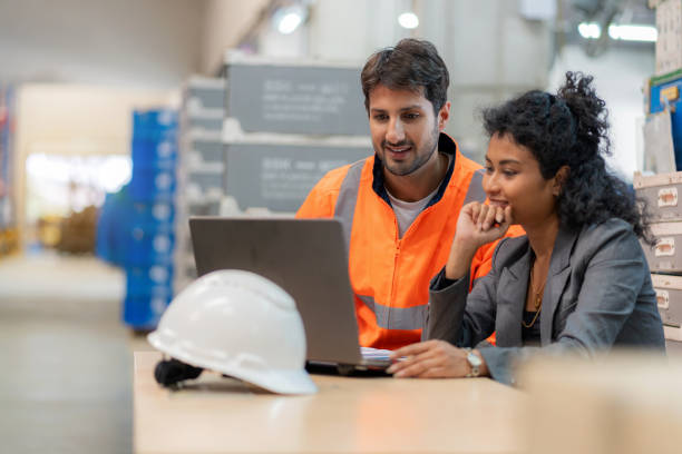 istock Warehouse manager and employee discussing logistics and supply chain improvements using a laptop. Industrial teamwork in a distribution center ensuring accuracy, efficiency, and occupational safety. Technology-driven inventory control in global business. 2197425740