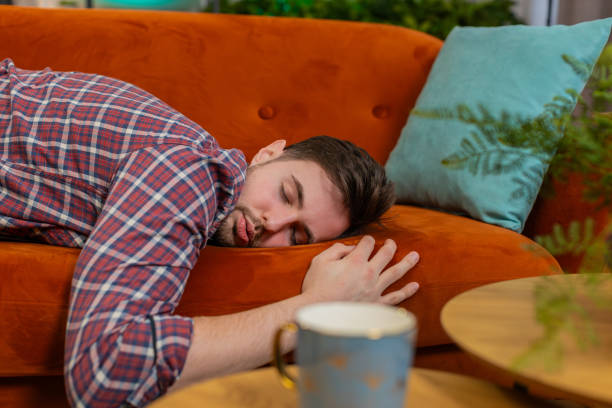 istock Exhausted young alcoholic drunk man flopped down on sofa falls asleep after party tired overworked 2197427909