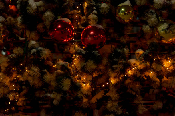 Christmas tree adorned with red and gold ornaments, glowing fairy lights, and snow-covered branches. A festive and cozy winter scene with a warm holiday atmosphere