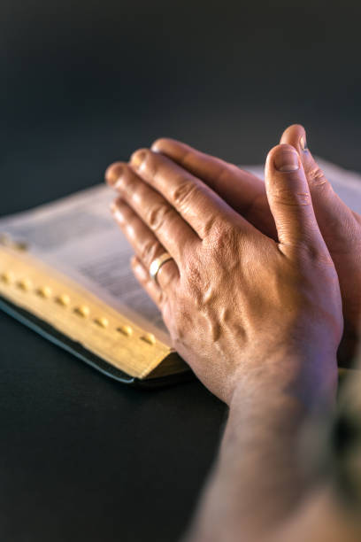 istock Hands on the Holy Bible. Prayer. Open Bible close-up. Religion concept. 2197430921