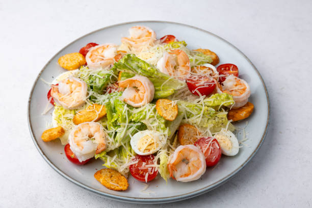 Caesar salad with tiger prawns, cherry tomatoes, croutons, parmesan cheese, quail eggs and romano lettuce. Traditional Americas