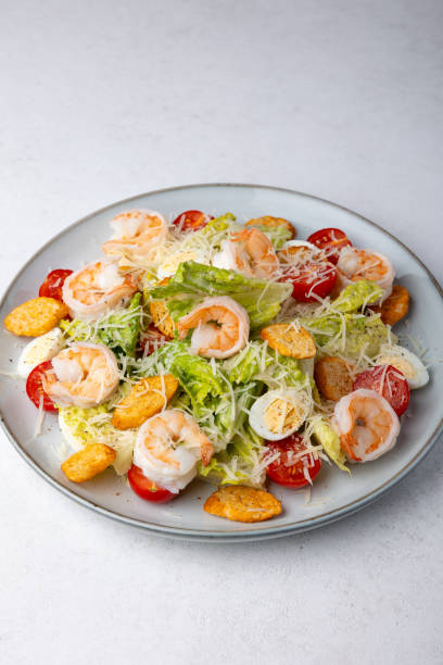 istock Caesar salad with tiger prawns, cherry tomatoes, croutons, parmesan cheese, quail eggs and romano lettuce. Traditional Americas 2197431049