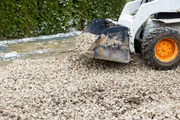 istock Construction Vehicle Spreading Gravel Near Snow Covered Evergreen Hedges 2197432722