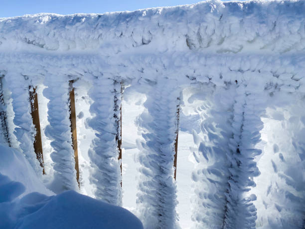 A breathtaking winter scene featuring a wooden railing completely covered in thick layers of frost and snow. The intricate ice formations create a surreal and otherworldly effect, showcasing the power of nature’s freezing temperatures. The contrast between the wooden structure and the heavy frost highlights the beauty of extreme winter conditions.