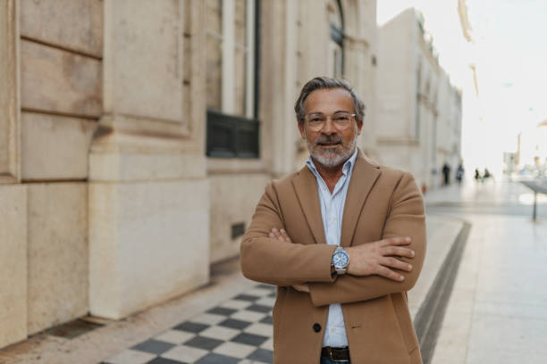 Portrait of a confident senior businessman with crossed arms in front of a building