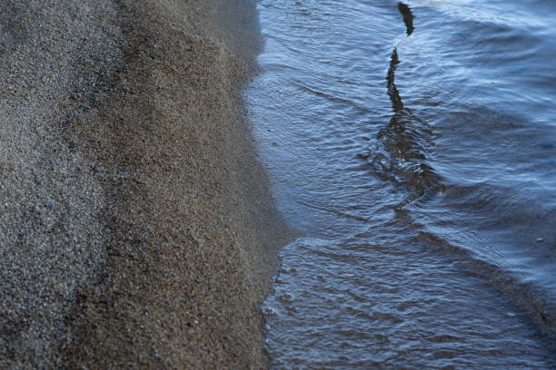 Clear lake water meeting a sandy beach late in the afternoon.