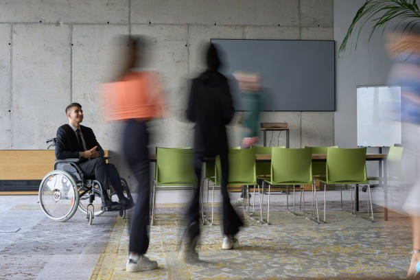 istock A diverse business team, working urgently around a conference table, collaborates on a meeting while their director, seated in a wheelchair, waits for their input 2197434377