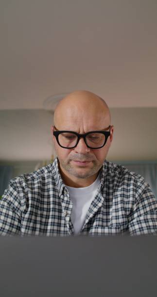 A man uses a laptop while sitting at a table at home, close-up