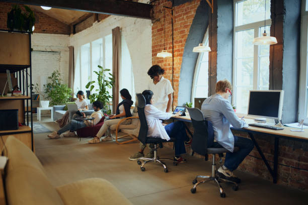 istock Productive coworking. Young people in modern office, maintaining productivity, working on gadgets. Positive ad comfortable atmosphere 2197435051