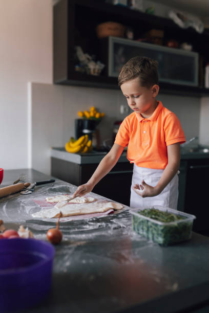 istock Happy cute little boy  preparing baking the dough in kitchen at home 2197435513