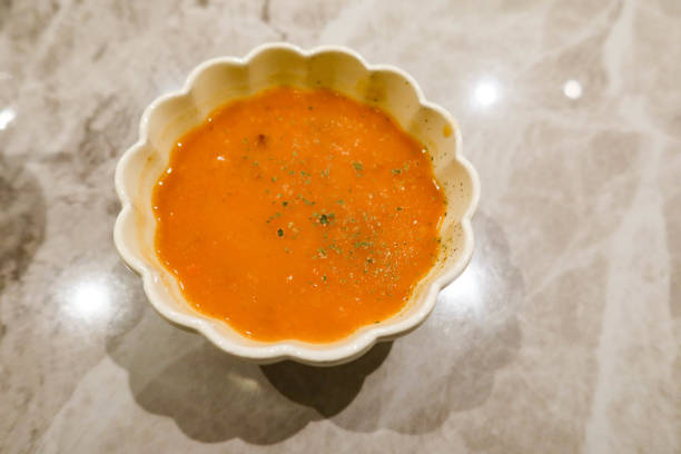close up of pumpkin cream soup in a floral pattern bowl on Marbled pattern table.
