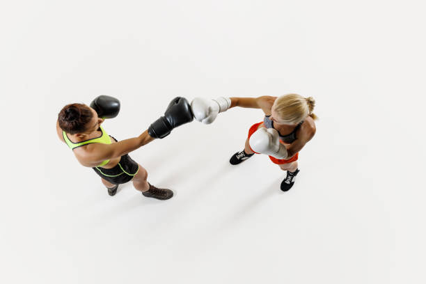 Women, focused boxers in action, displaying athleticism and determination, training isolated on white background. Top view. Concept of combat sport, martial arts, strength, endurance