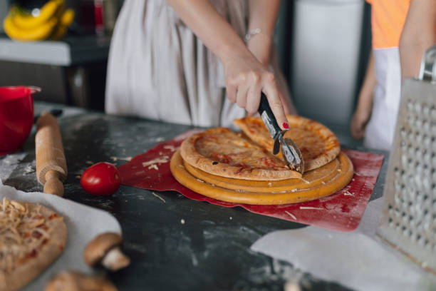 Woman cutting the baked pizza into pieces