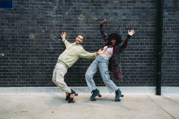 istock Young couple having fun roller skating against a brick wall 2197440140