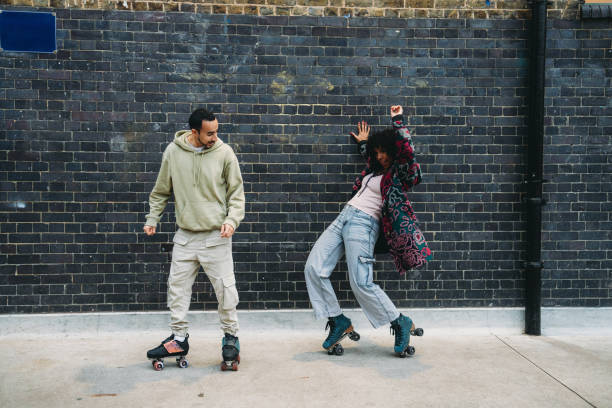istock Young couple roller skating and dancing against a brick wall 2197440157