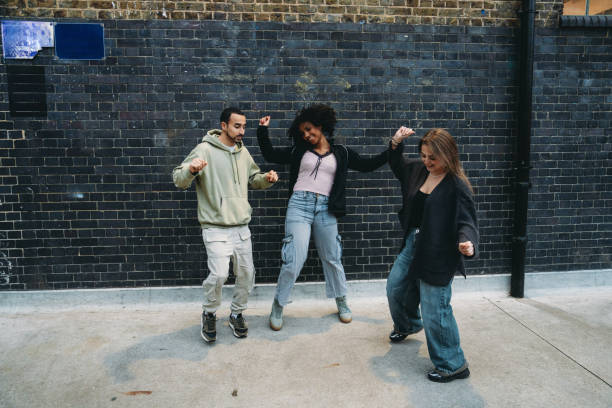 istock Three friends dancing in the street against a black brick wall 2197440188