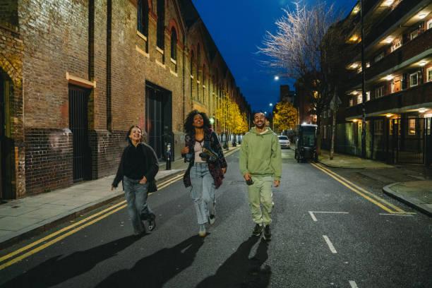istock Three young friends walking down a London street at night 2197440349