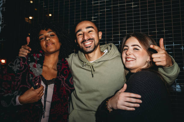 istock Three friends embracing and smiling at night 2197440508