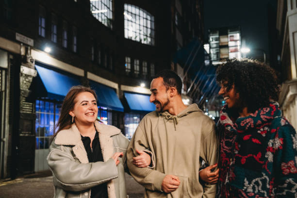 istock Three friends walking and talking at night in London 2197440598