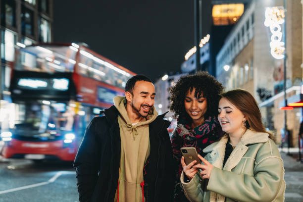 istock Young friends looking at smartphone in London at night 2197440608