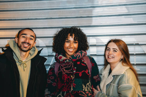 istock Three young adults smiling and posing in front of a metal storefront 2197440611