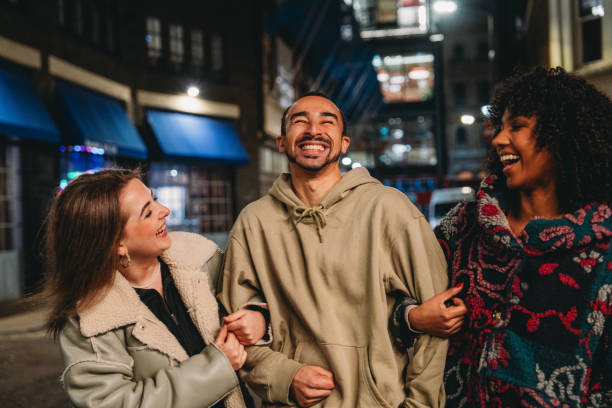 istock Three friends laughing and walking together at night 2197440614