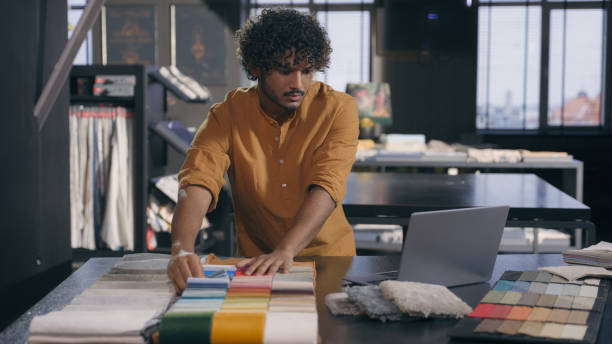 istock Male fashion designer interior decorator choosing samples color fabric at workshop Arabian Indian man guy tailor stylist dressmaker choose compare woolen material cloth collection clothes accessories 2197449182
