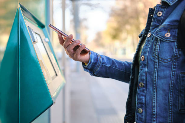 istock Woman using smartphone to purchase public transport ticket at automatic machine. unrecognizable person. Public Transport and technology concept 2197449256