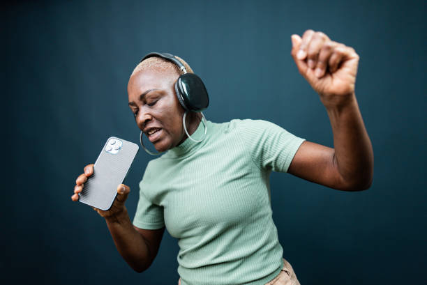 istock Mature woman dancing and singing at blue background 2197449391