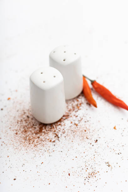 pepper and salt shaker chili peppers on a white background sprinkled with a mixture of peppers and salt