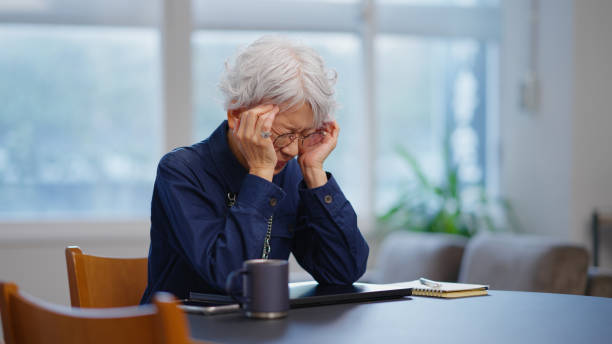 stressed older businesswoman at office with laptop and reusable mug - cáu gắt hình ảnh sẵn có, bức ảnh & hình ảnh trả phí bản quyền một lần