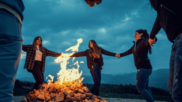 istock Friends holding hands and dancing around bonfire at dusk 2197452022