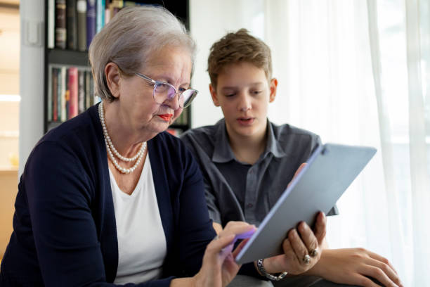 istock Grandson Teaching Grandma Digital Technology in Modern Living Room 2197454859
