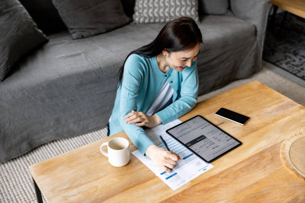 istock Asian woman at home paying bills online using her digital tablet 2197455430