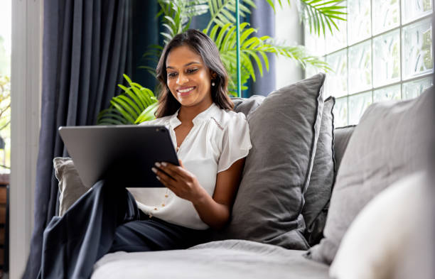 istock Businesswoman working on her tablet while sitting on the sofa at home 2197455436