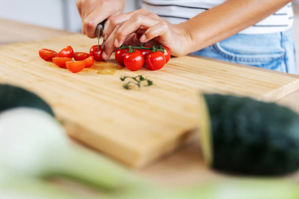 istock Woman chopping cherry tomatoes on cutting board, preparing salad in kitchen 2197455996