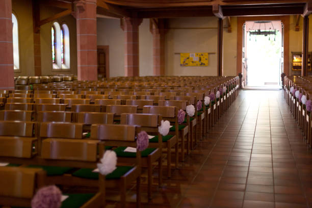 Two ornate chairs adorned with flowers and fabric are prepared for a wedding ceremony in a church. The decor sets a tone of romance and celebration, ideal for a special event or a wedding-related