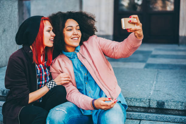 istock Young girls relaxing on urban steps and taking selfie 2197458274