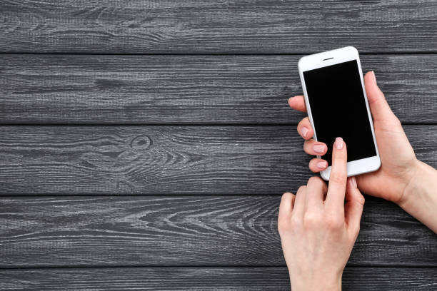 istock Smartphone in female hands on wooden background 2197458403