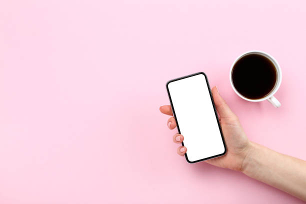 istock Smartphone in hand with cup of coffee on pink background 2197458660