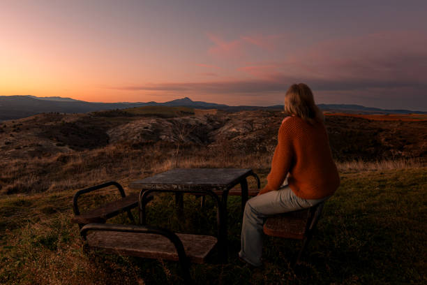 One woman sitted in a bench looking the sunset in a nture landscape
