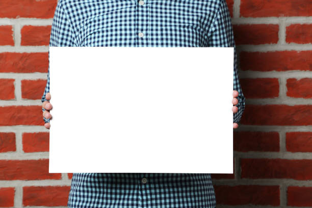 istock Man holding blank poster on brick wall background 2197466116