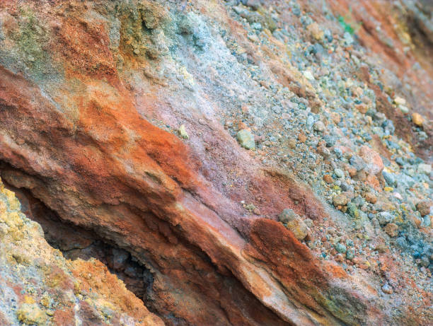 Volcanic rocks on Mount Etna, Sicily, Italy with detailed textures of colorful stones in the foreground with a blurred volcanic ridge fading into the background.